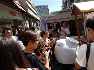 (市民游客在包强前摩肩接踵,争相合影和购买美食)